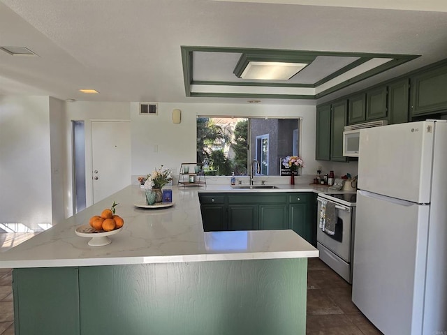 kitchen with a raised ceiling, sink, white appliances, and green cabinets