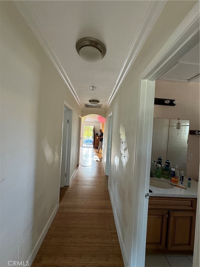 hallway with sink, crown molding, and hardwood / wood-style flooring