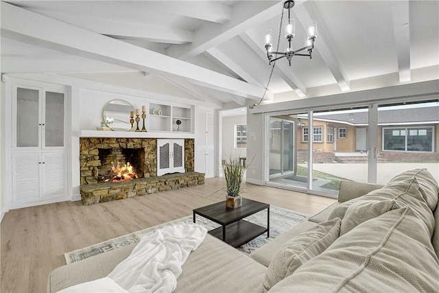 living room with lofted ceiling with beams, a stone fireplace, light wood-type flooring, and a chandelier