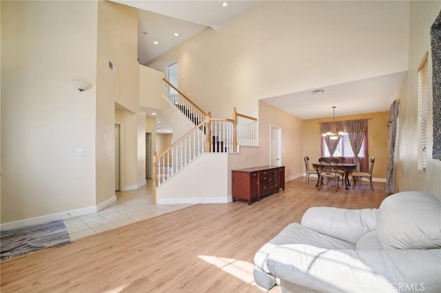 living room with an inviting chandelier, a high ceiling, and light hardwood / wood-style flooring