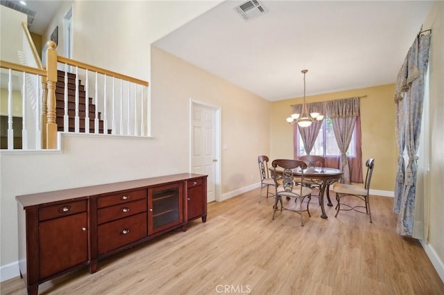 dining space with light hardwood / wood-style flooring and a chandelier