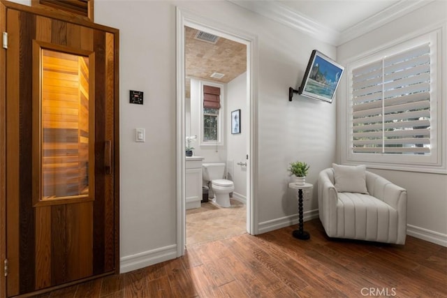 living area featuring visible vents, a sauna, baseboards, ornamental molding, and wood finished floors