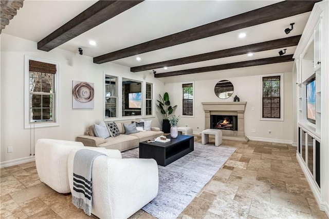 living room featuring a wealth of natural light, baseboards, and a warm lit fireplace