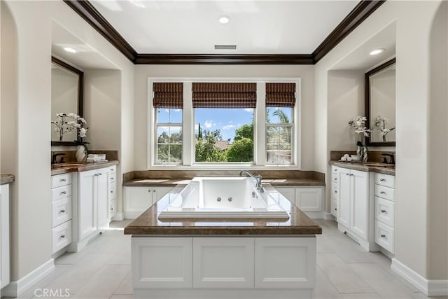 bathroom with a tub with jets, visible vents, a sink, ornamental molding, and tile patterned floors