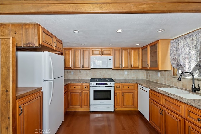 kitchen featuring tasteful backsplash, light stone countertops, dark wood-type flooring, sink, and white appliances