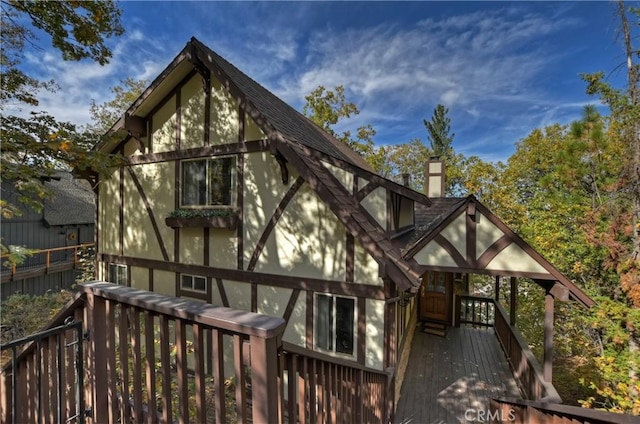 back of house with a wooden deck, a shingled roof, a chimney, and fence