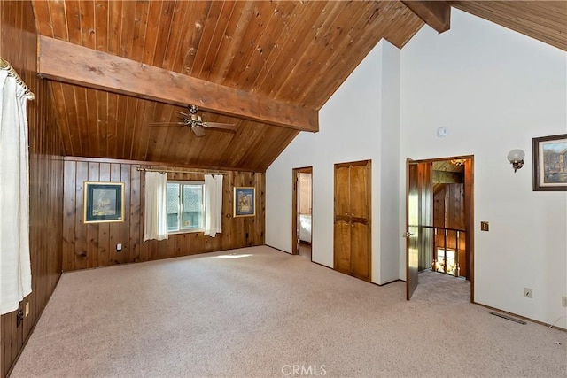 interior space featuring beamed ceiling, wood walls, wood ceiling, and carpet floors