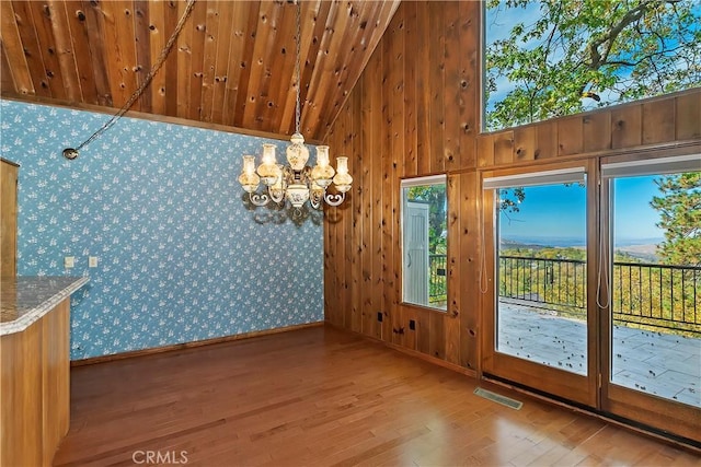 unfurnished dining area with visible vents, lofted ceiling, plenty of natural light, and wood finished floors