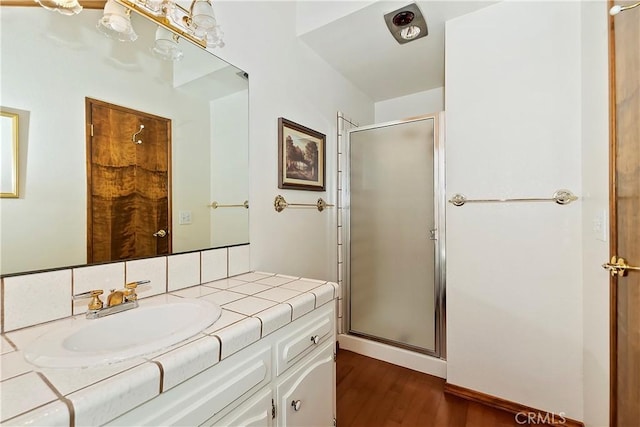 bathroom with vanity, wood finished floors, and a stall shower