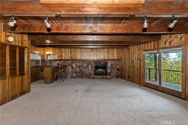 unfurnished living room with beamed ceiling, carpet flooring, and wood walls