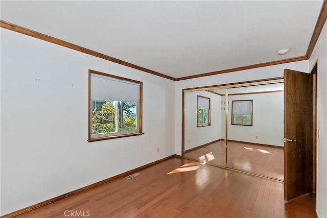 spare room featuring visible vents, wood finished floors, baseboards, and ornamental molding