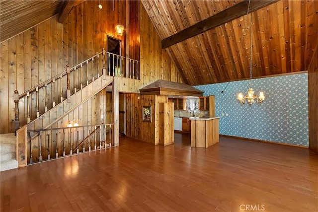 unfurnished living room with wallpapered walls, beamed ceiling, wood finished floors, a notable chandelier, and high vaulted ceiling