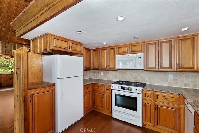 kitchen featuring white appliances, stone counters, dark wood-type flooring, brown cabinets, and backsplash