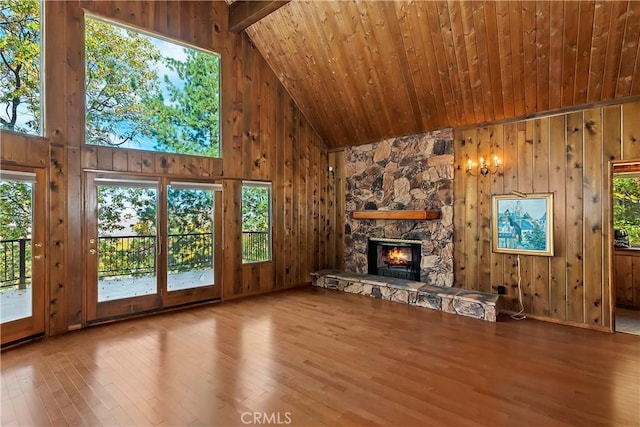 unfurnished living room with wood finished floors, a fireplace, and wood walls