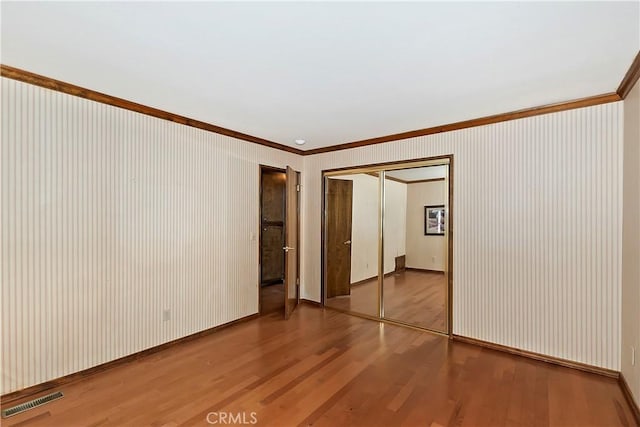 spare room featuring light wood finished floors, visible vents, baseboards, and ornamental molding