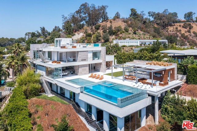 back of property with a patio, a balcony, and a pool with hot tub