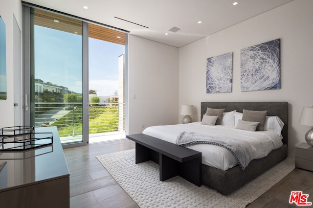 bedroom with access to outside, hardwood / wood-style flooring, and a wall of windows