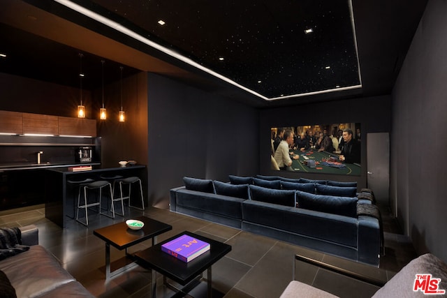 home theater room featuring tile flooring and a raised ceiling