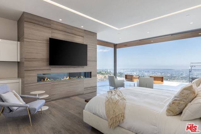 bedroom featuring hardwood / wood-style floors, expansive windows, tile walls, and a fireplace