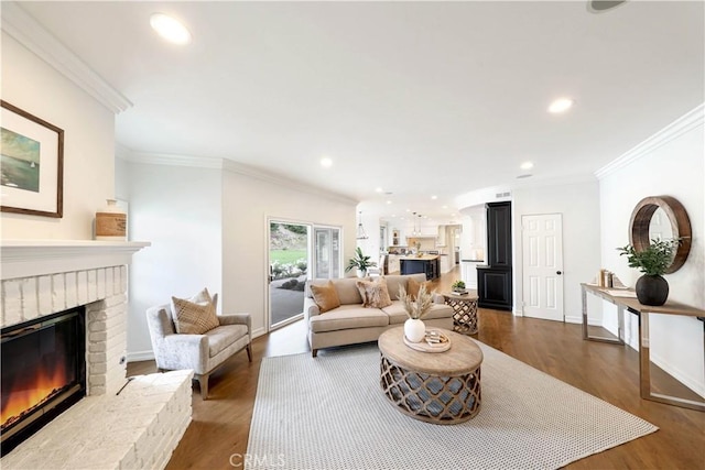 living room featuring crown molding, wood-type flooring, and a brick fireplace