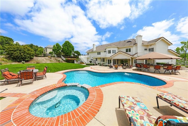 view of swimming pool with a lawn, a patio area, a bar, and an in ground hot tub