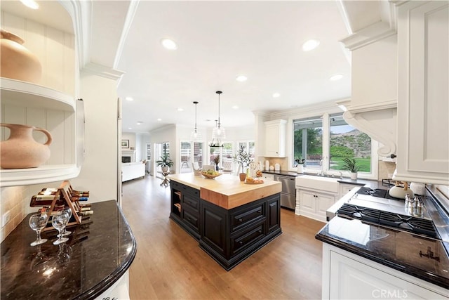 kitchen featuring white cabinets, wooden counters, a kitchen island, and stainless steel dishwasher