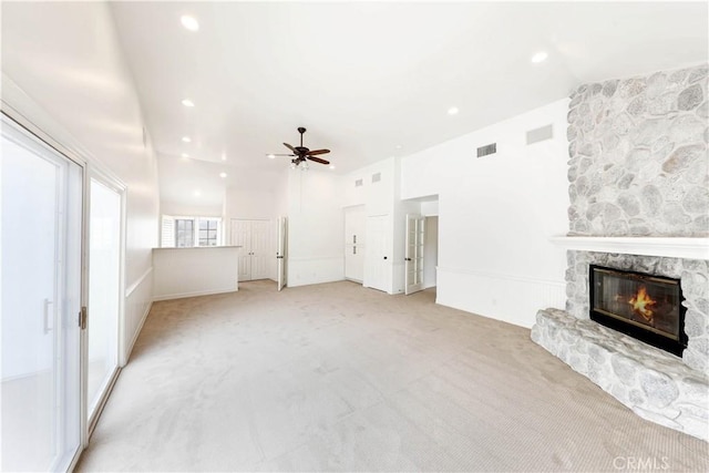 unfurnished living room with a stone fireplace, ceiling fan, light colored carpet, and lofted ceiling