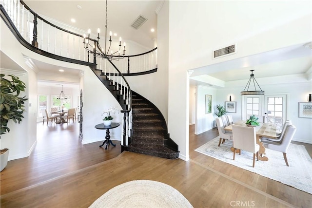 entrance foyer featuring hardwood / wood-style floors, french doors, ornamental molding, and a high ceiling