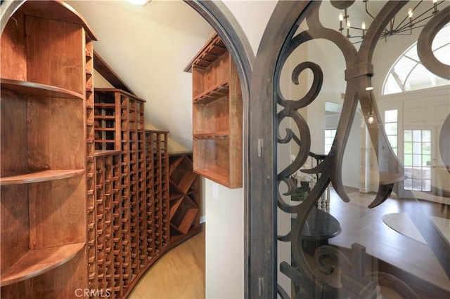 wine area with wood-type flooring and a notable chandelier