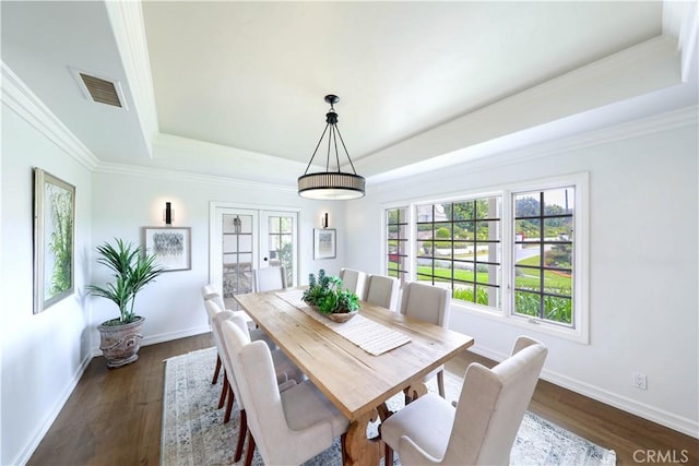 dining space featuring a raised ceiling, crown molding, and dark wood-type flooring