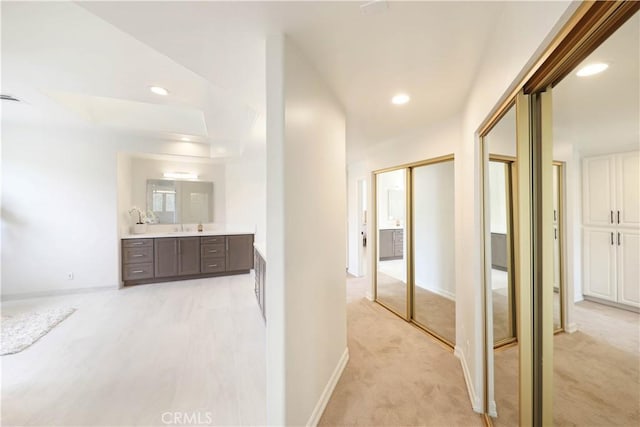 hall featuring light colored carpet and sink