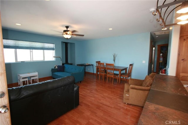 living room featuring a wood stove, ceiling fan, and wood-type flooring