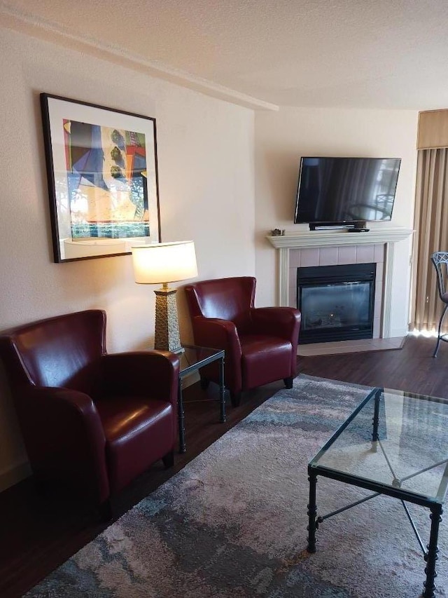 living room featuring dark hardwood / wood-style floors and a tiled fireplace