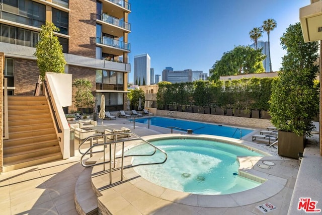 view of pool with a patio area and a hot tub