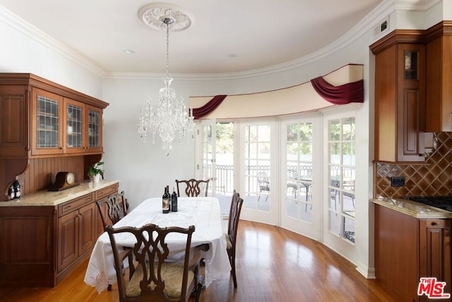 dining room featuring light hardwood / wood-style floors, crown molding, and an inviting chandelier