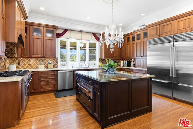 kitchen featuring high end appliances, light stone countertops, backsplash, and light hardwood / wood-style flooring