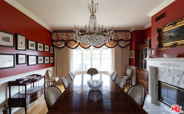 dining space with a chandelier, ornamental molding, a fireplace, and wood-type flooring