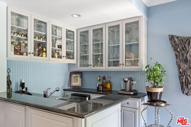 bar featuring dark stone counters and white cabinetry