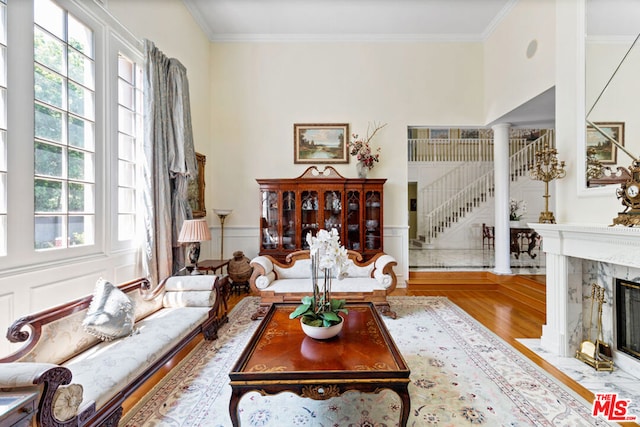 living room with a premium fireplace, a wealth of natural light, hardwood / wood-style flooring, and crown molding