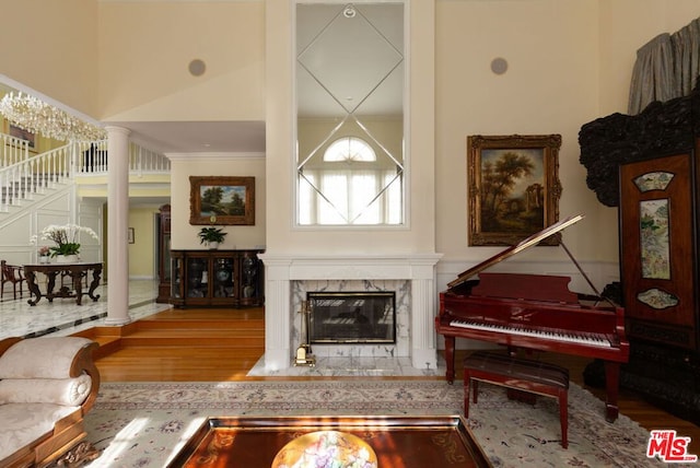 living room featuring a high ceiling, a premium fireplace, hardwood / wood-style flooring, and decorative columns