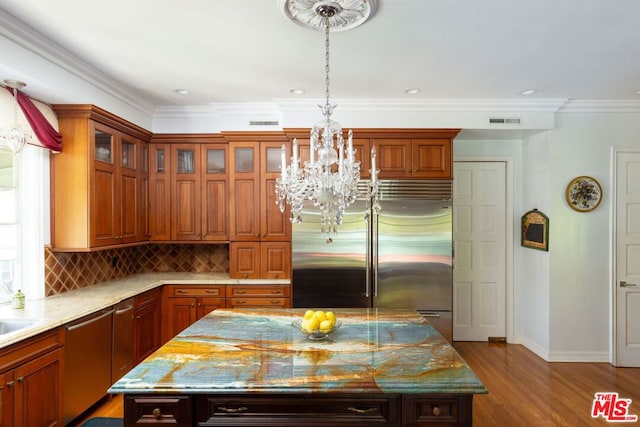 kitchen with a center island, light stone countertops, hardwood / wood-style floors, backsplash, and built in refrigerator