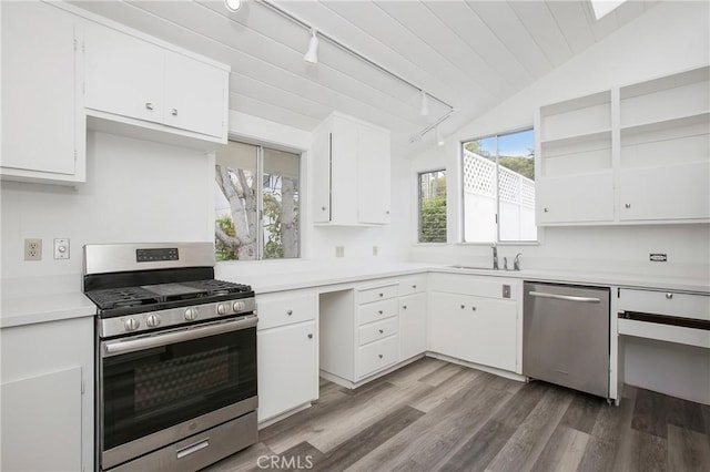 kitchen featuring white cabinets, track lighting, lofted ceiling, and appliances with stainless steel finishes