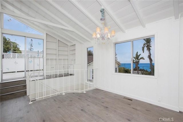 spare room featuring vaulted ceiling with beams, a water view, a notable chandelier, and hardwood / wood-style flooring