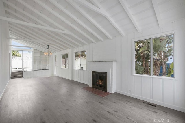 unfurnished living room featuring vaulted ceiling with beams, a chandelier, wood-type flooring, and a brick fireplace