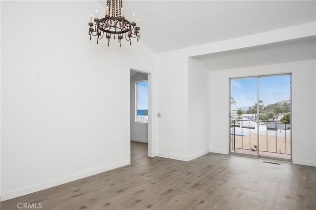 unfurnished room featuring wood-type flooring, vaulted ceiling, and an inviting chandelier