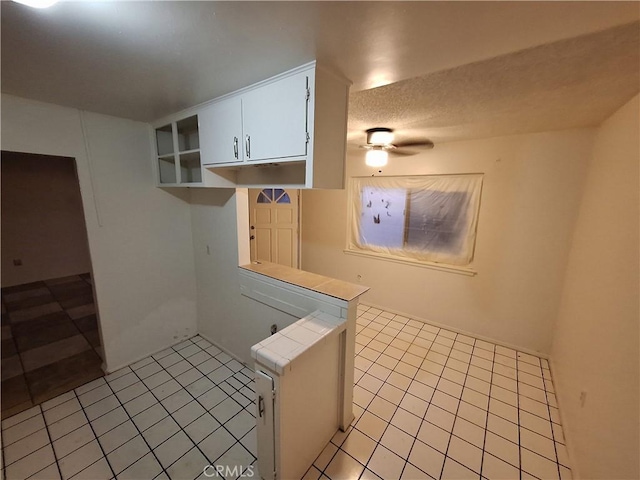 kitchen featuring white cabinetry, tile counters, light tile patterned flooring, and a textured ceiling