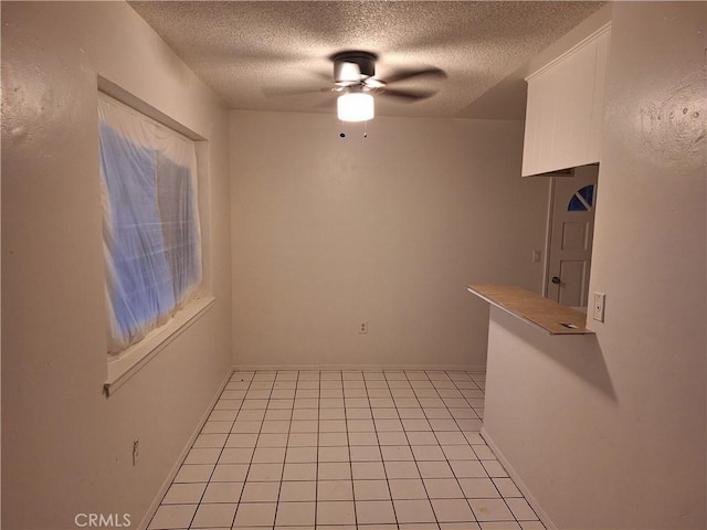 spare room with ceiling fan, light tile patterned floors, and a textured ceiling