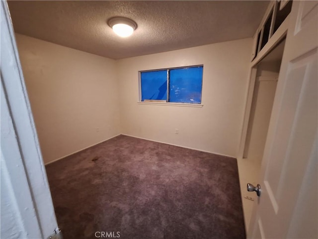 unfurnished bedroom with a closet, dark carpet, and a textured ceiling