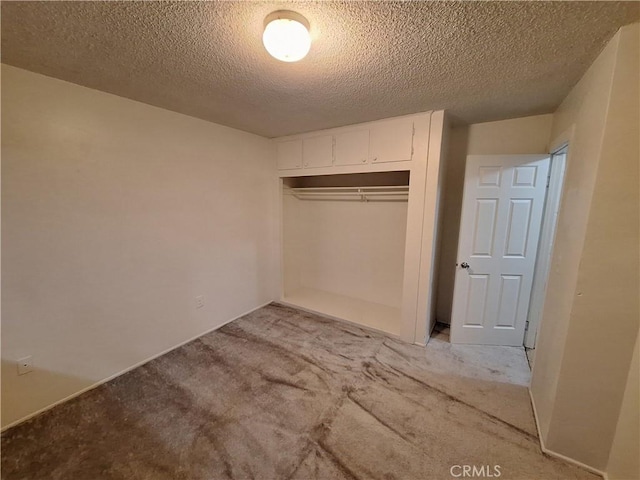 unfurnished bedroom featuring a textured ceiling, light carpet, and a closet