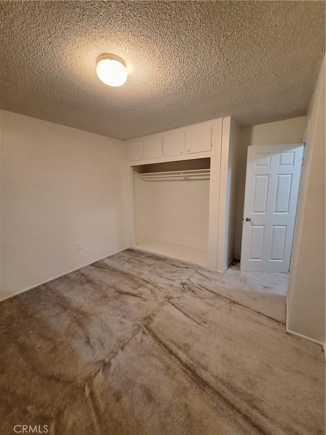 unfurnished bedroom featuring light carpet, a textured ceiling, and a closet